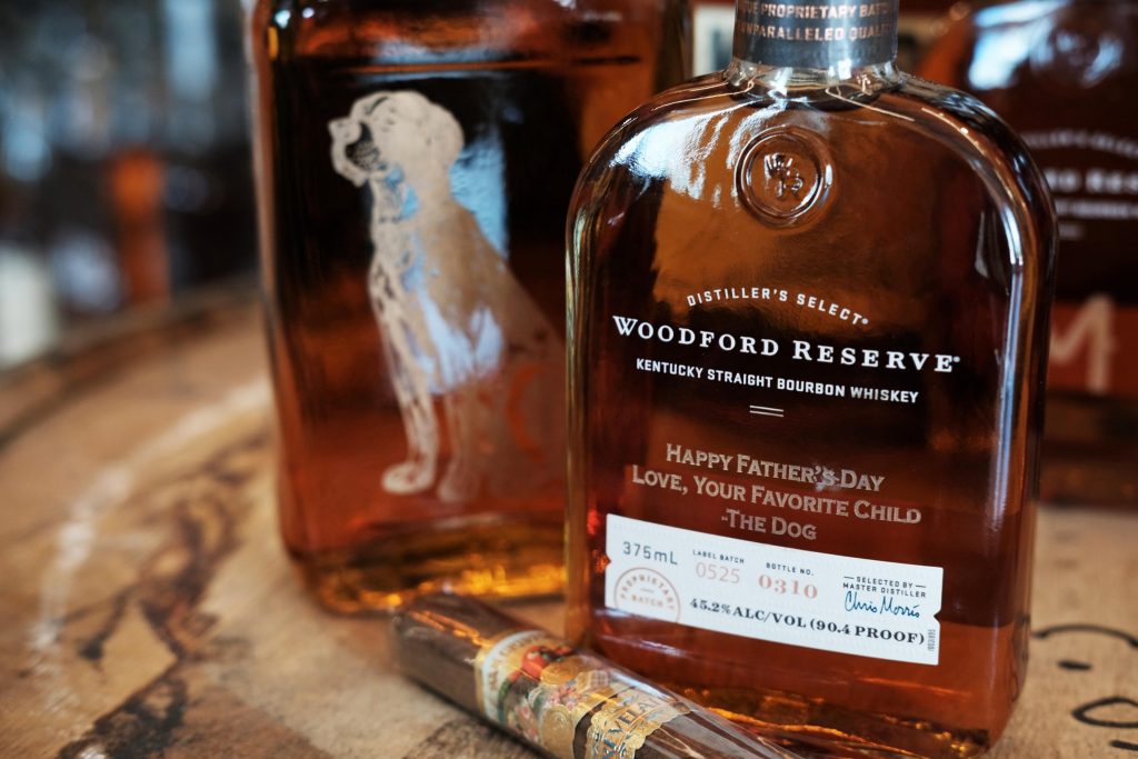 A bottle of whiskey and a cigar on top of a table.