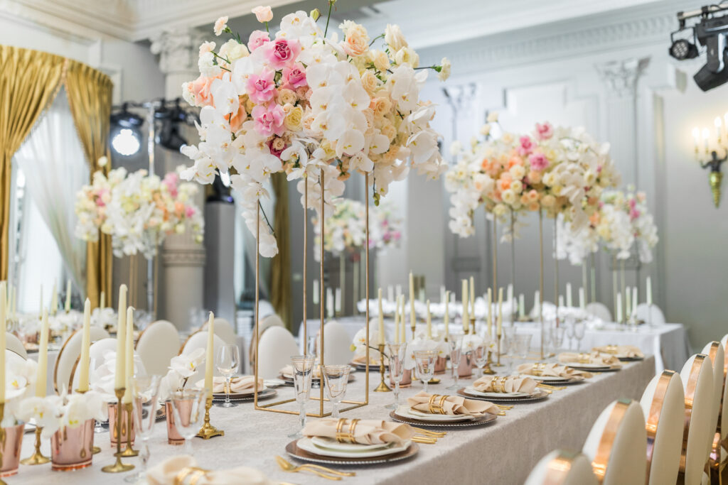 A table set with plates and candles, flowers on stands.